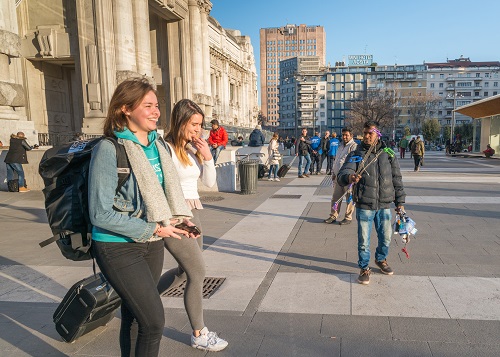 A street seller and tourists at Milan's Central Station