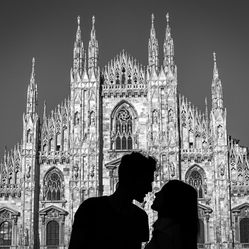 Silhouette of a young couple kiss in front of Milan' s Gothic cathedral