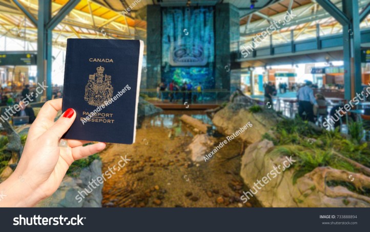 stock-photo-hand-holding-a-canadian-passport-at-vancouver-international-airport-lounge-733888894