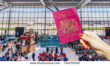 stock-photo-hand-holding-uk-passport-with-busy-airport-waiting-lounge-and-airplanes-in-background-734235550