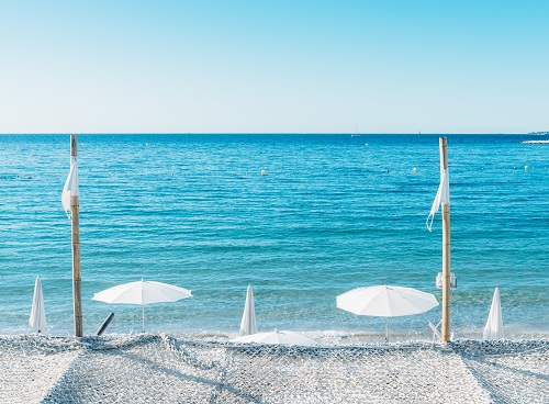 Giant white beach umbrella next to the ocean against a blue sky