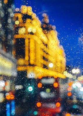 Emotional melancholic abstract background with defocused lights bokeh in London, UK behind rain drops in window glass, Focus on few drops due to the shallow depth of field