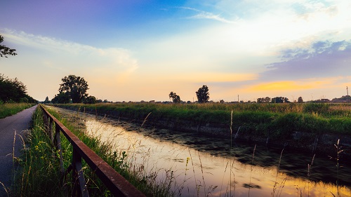 Empty cycling path along the Naviglio Pavese, canal at sunset. The canal stretches for 30km from Pavia to Milan in Lombardy, northern Italy.