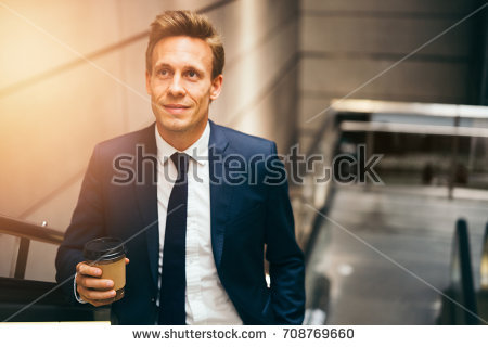 stock-photo-smiling-young-executive-in-a-suit-drinking-a-coffee-and-riding-up-an-escalator-in-a-subway-station-708769660