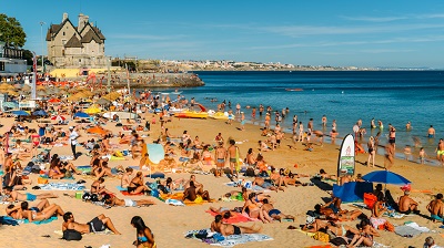 Crowded sandy beach in Cascais near Lisbon, Portugal during the summer. This beach is known as Praia da Conceicao