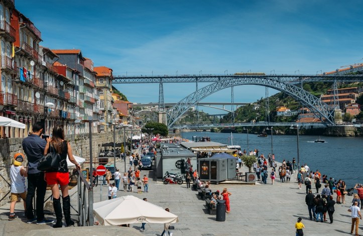 Couple at Ribeira docks facing Dom Luis I Bridge over Douro River and Gaia town, Porto, Portugal