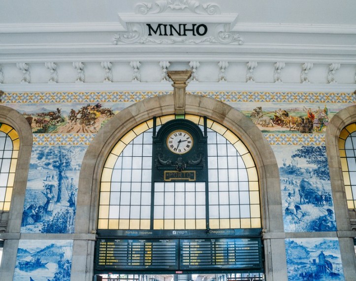 Clock of the historical Sao Bento train station in Porto, Portugal. Wall is covered in blue azulejo tiles