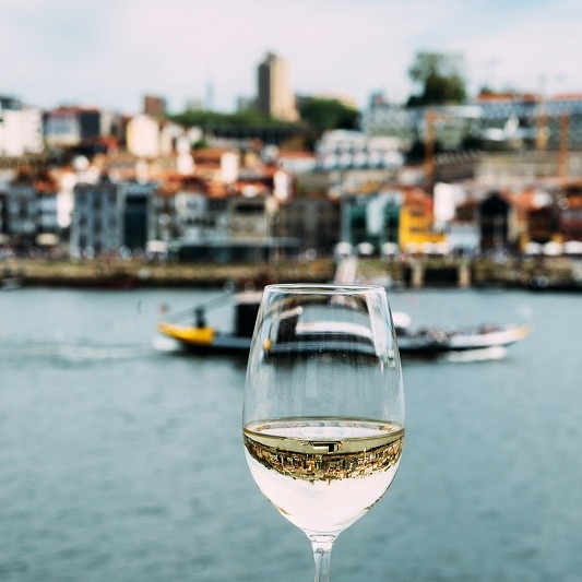 White wine glass overlooking Vila Nova de Gaia riverbank, Porto, Portugal