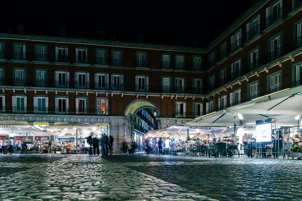 People walking and sitting at restaurant terraces at Plaza Mayor Madrid, Spain at night