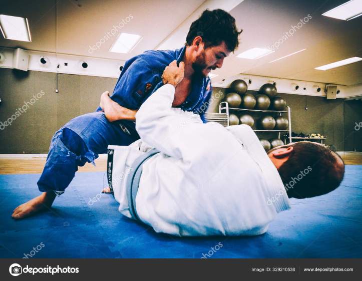 Two young men practice Brazilian Jiu-Jitsu sparring, a grappling type martial arts with a kimono gi - NOT STAGED CONTENT OR AT CLOSED EVENT
